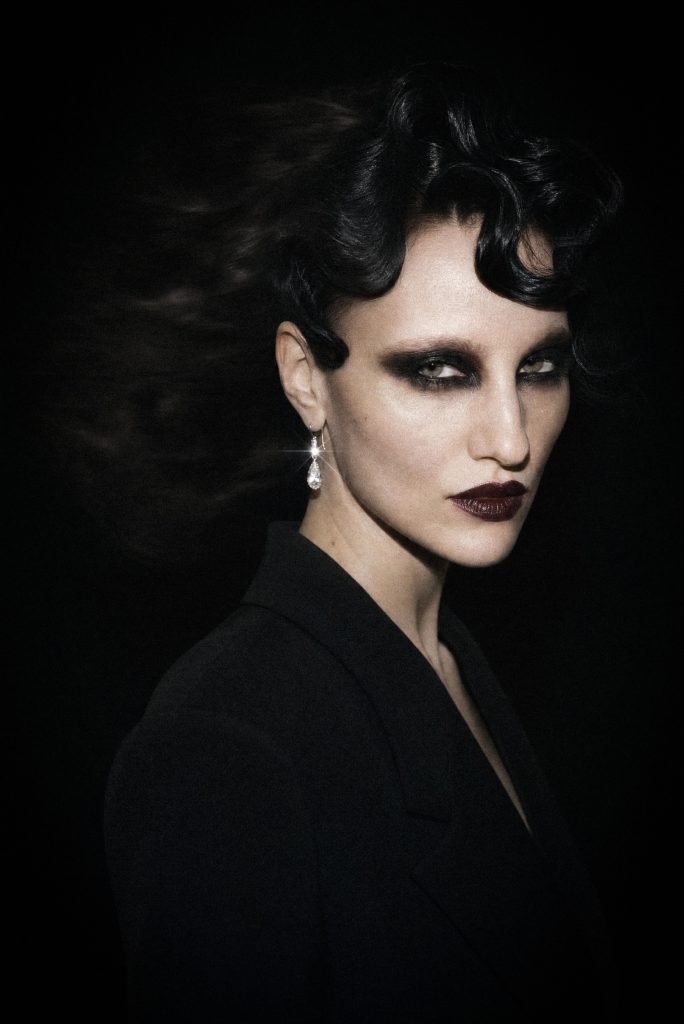 Noir beauty portrait, glossy black finger waves, smoky eyes, dark berry lips and a sparkling drop earring against black — The OysterVerse by Franka Louisa